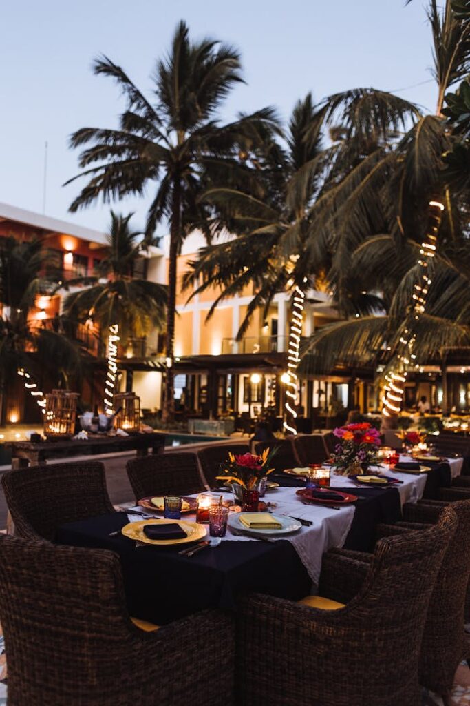 Nighttime al fresco dining at a tropical resort with palm trees and ambient lighting.